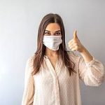 Woman in mask giving thumbs up