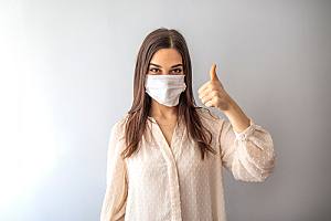 Woman in mask giving thumbs up