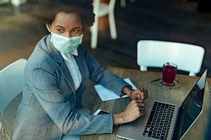 Employee in mask on laptop