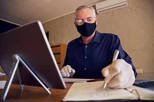 Small business owner in mask on computer