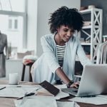 woman at her small business typing on her laptop and interacting with customers