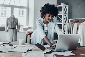 woman at her small business typing on her laptop and interacting with customers