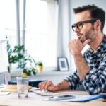 Thoughtful freelancer looking at computer while working from home office