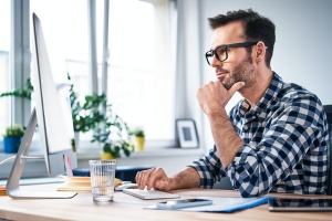 Thoughtful freelancer looking at computer while working from home office