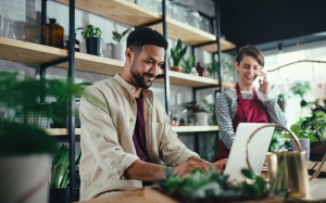 Shop assistants with laptop working in potted plant store, small business concept.